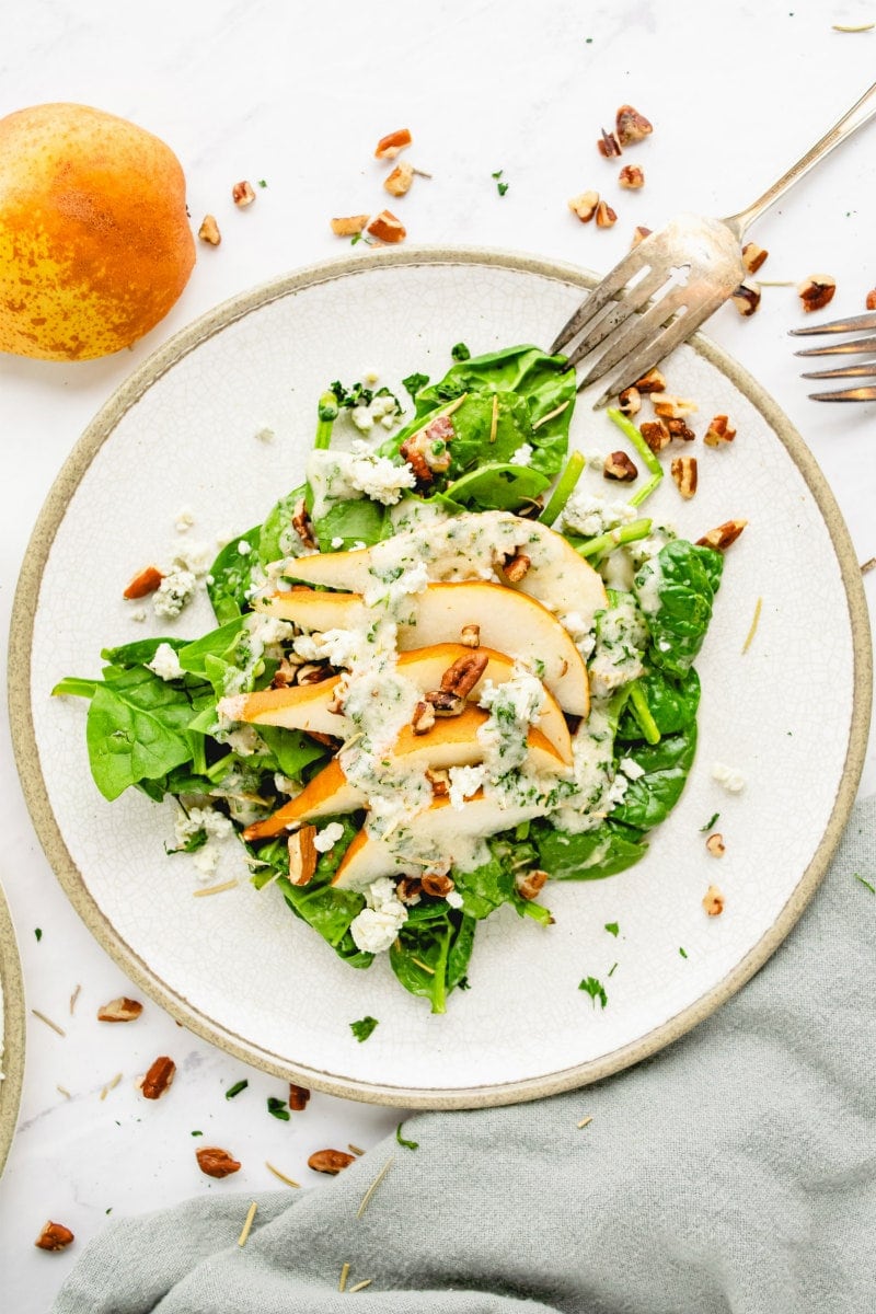 spinach and pear salad on white plate with fork