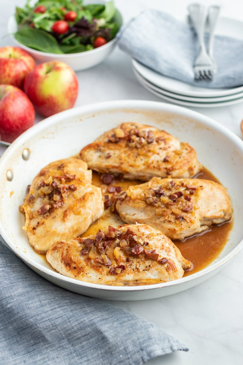 chicken with cider and bacon sauce in white skillet