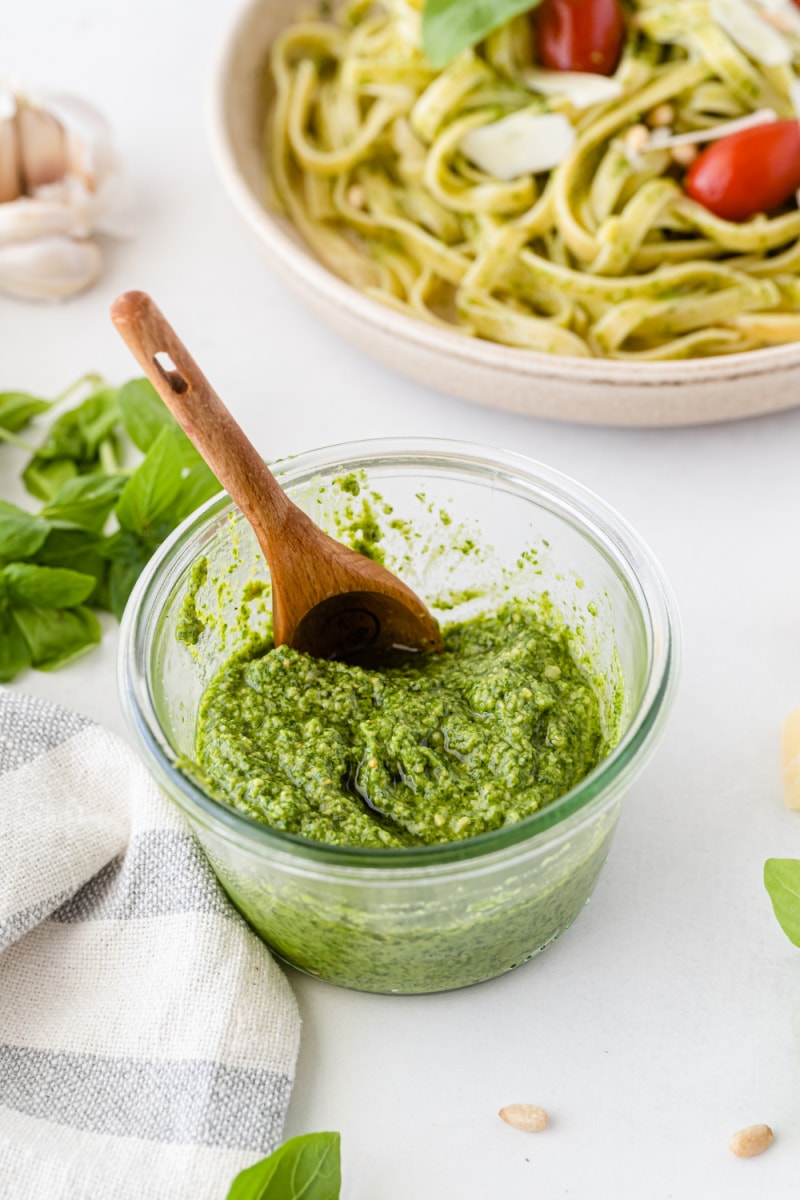 jar of classic pesto sauce in glass bowl with wooden spoon
