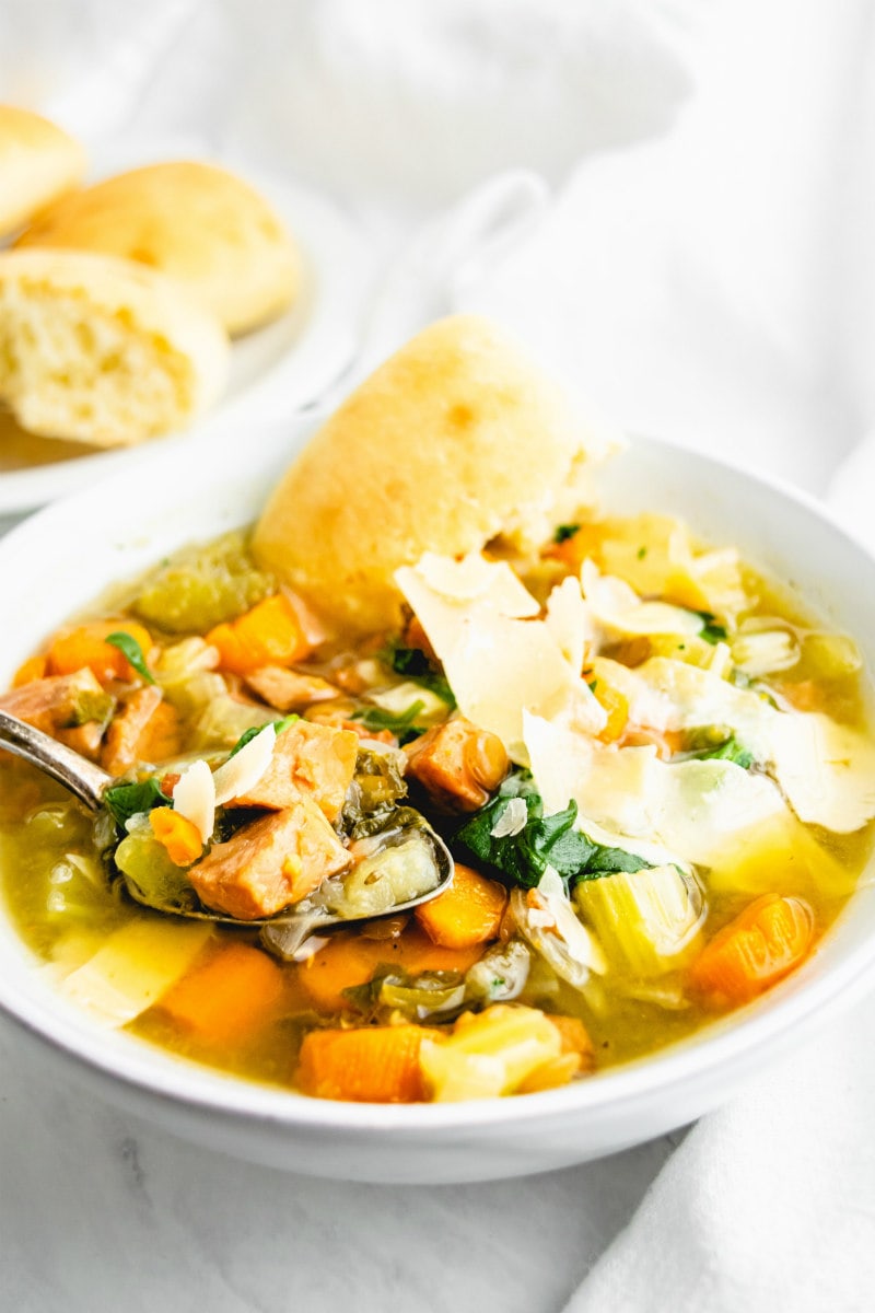 ham and lentil soup in a white bowl with piece of bread