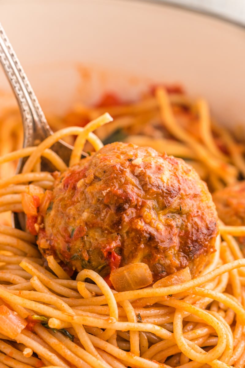 close up meatball sitting on top of spaghetti
