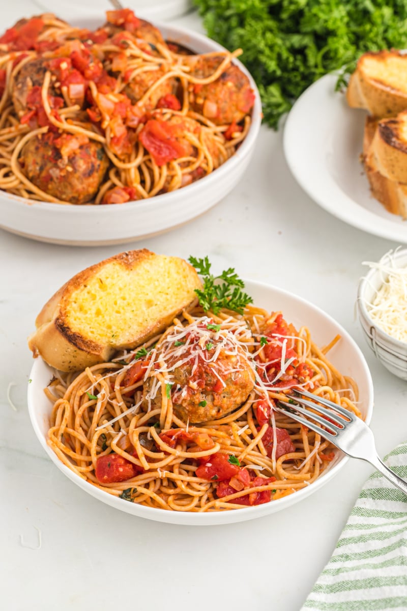 servings of spaghetti and meatballs with garlic bread in bowls