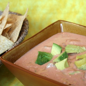 spicy hummus avocado dip in a bowl with chips