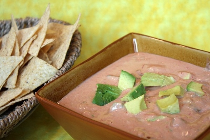 spicy hummus avocado dip in a bowl with chips