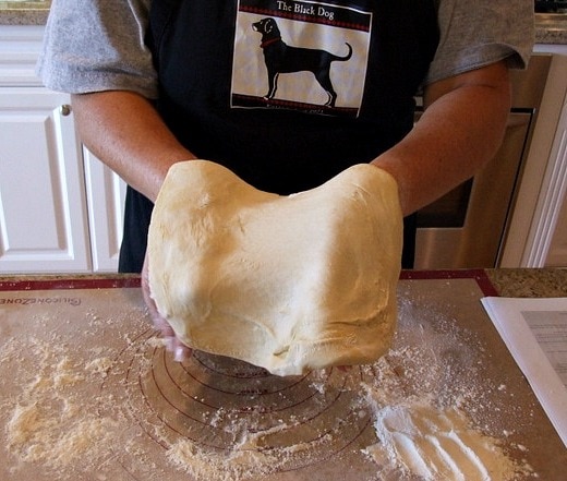 Person holding basic pizza dough and stretching