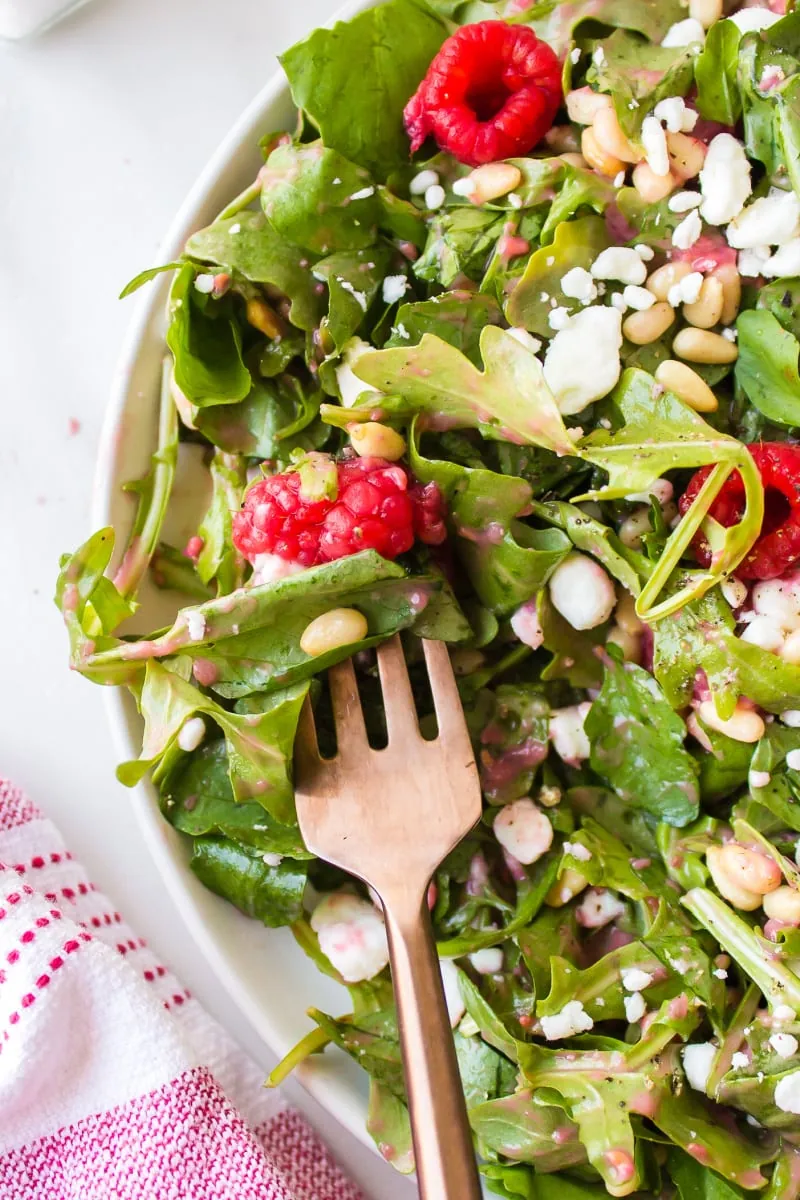 green salad with goat cheese and raspberry with fork