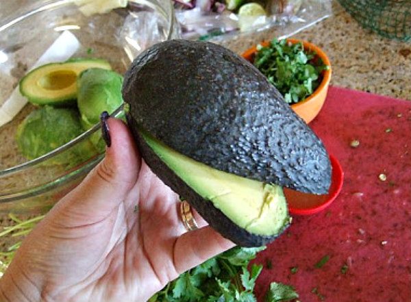 Avocado cut open hand holding it