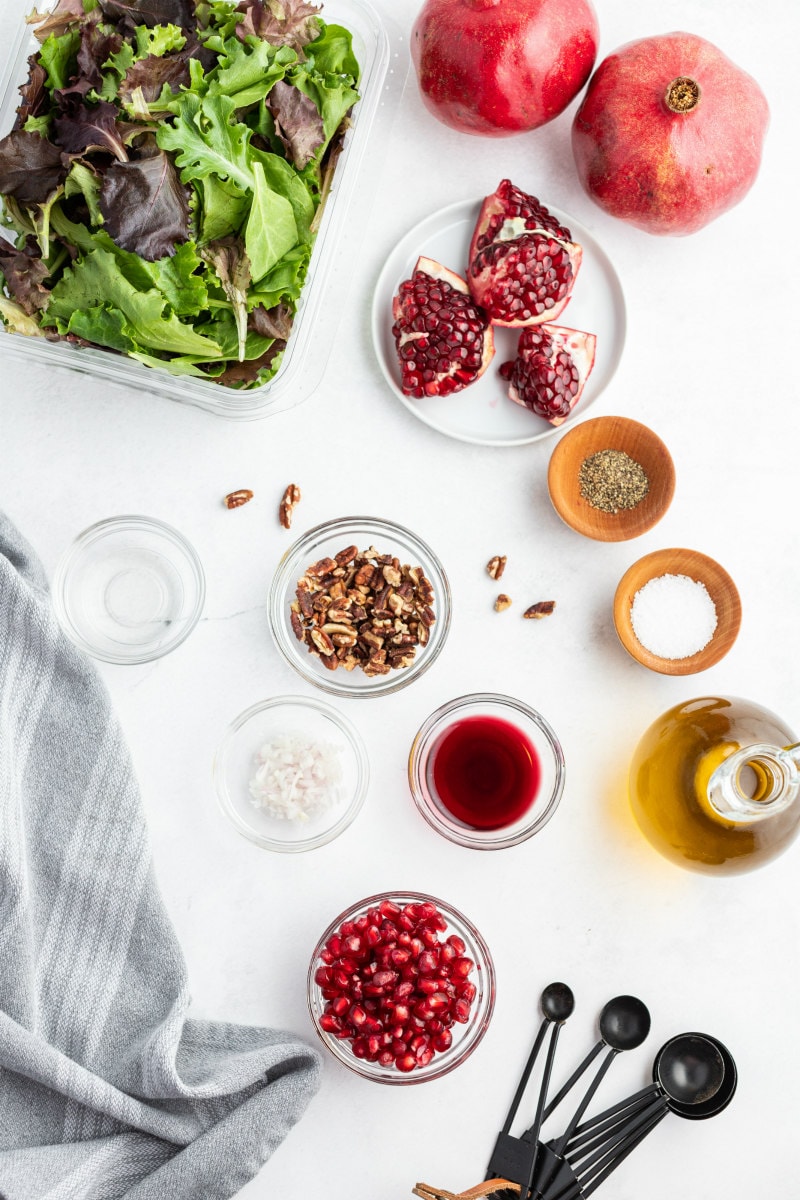 ingredients displayed in bowls for mixed green pomegranate salad