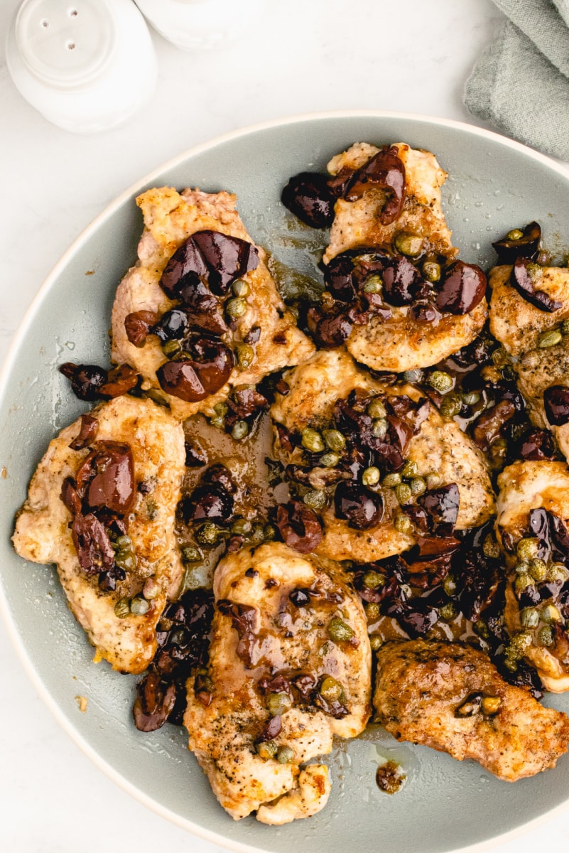 plate of pork with olives and capers