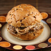 root beer pulled pork sandwich sitting on a brown and white plate with orange and yellow polka dots