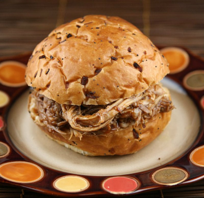 root beer pulled pork sandwich sitting on a brown and white plate with orange and yellow polka dots