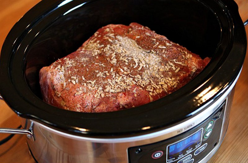 pork roast topped with spices sitting in a slow cooker getting ready to cook