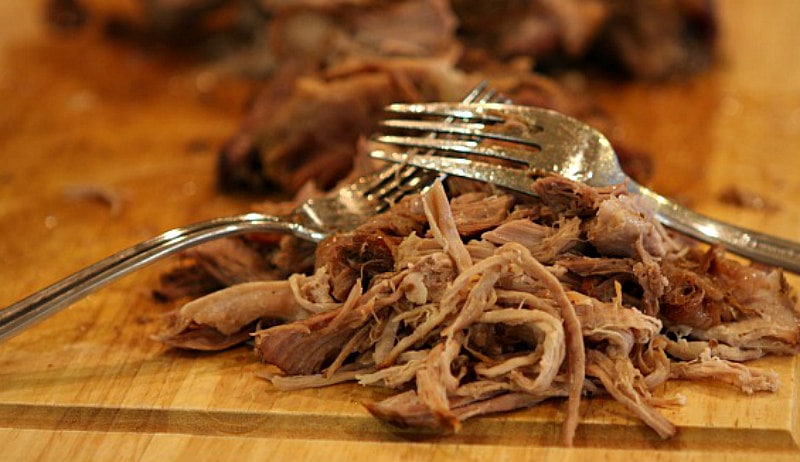 fork pulling pork on a cutting board