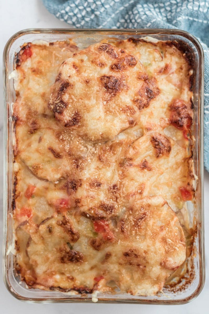 scalloped potatoes with peppers and swiss cheese in baking dish