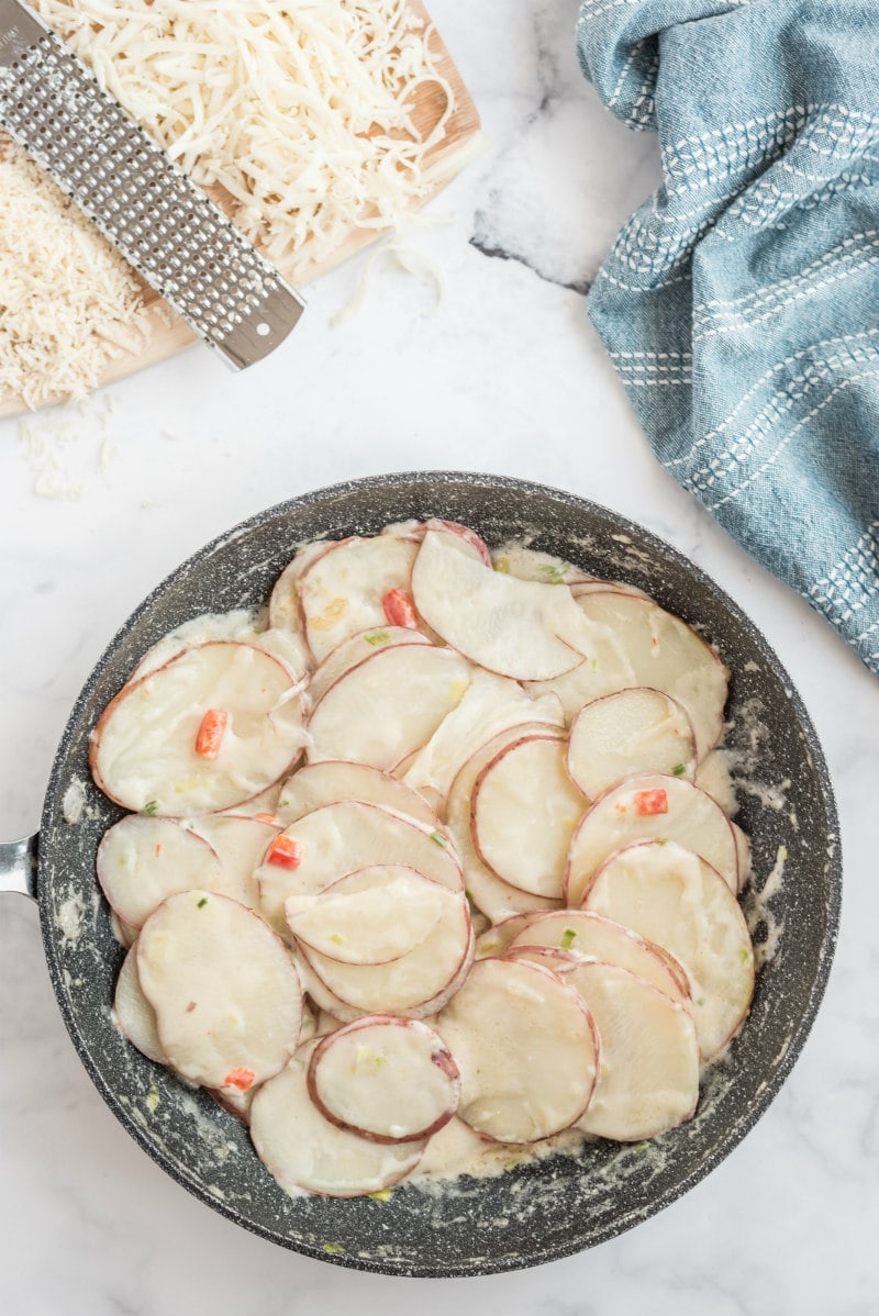 scalloped potatoes mixed with sauce in a skillet