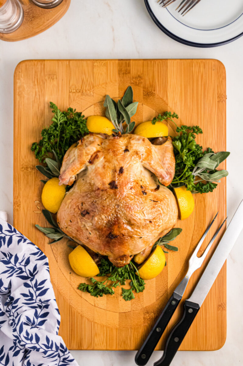 roasted chicken on a board with lemons