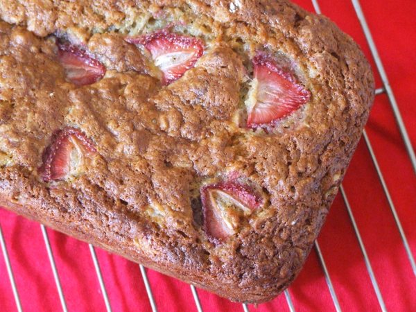 overhead shot of strawberry oatmeal banana bread loaf on a cooling rack over a red cloth napkin