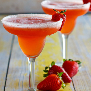 two strawberry margaritas in margarita glasses garnished with strawberries