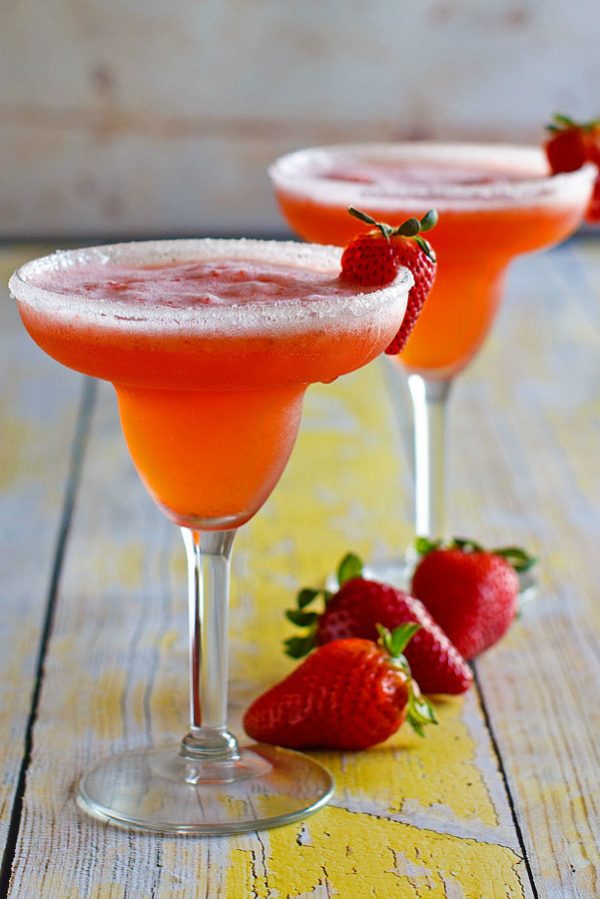 Two Strawberry Margaritas in margarita glasses garnished with fresh strawberries