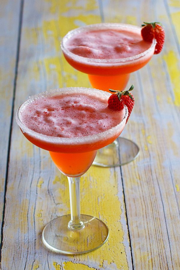 Two Strawberry Margaritas in margarita glasses garnished with fresh strawberries