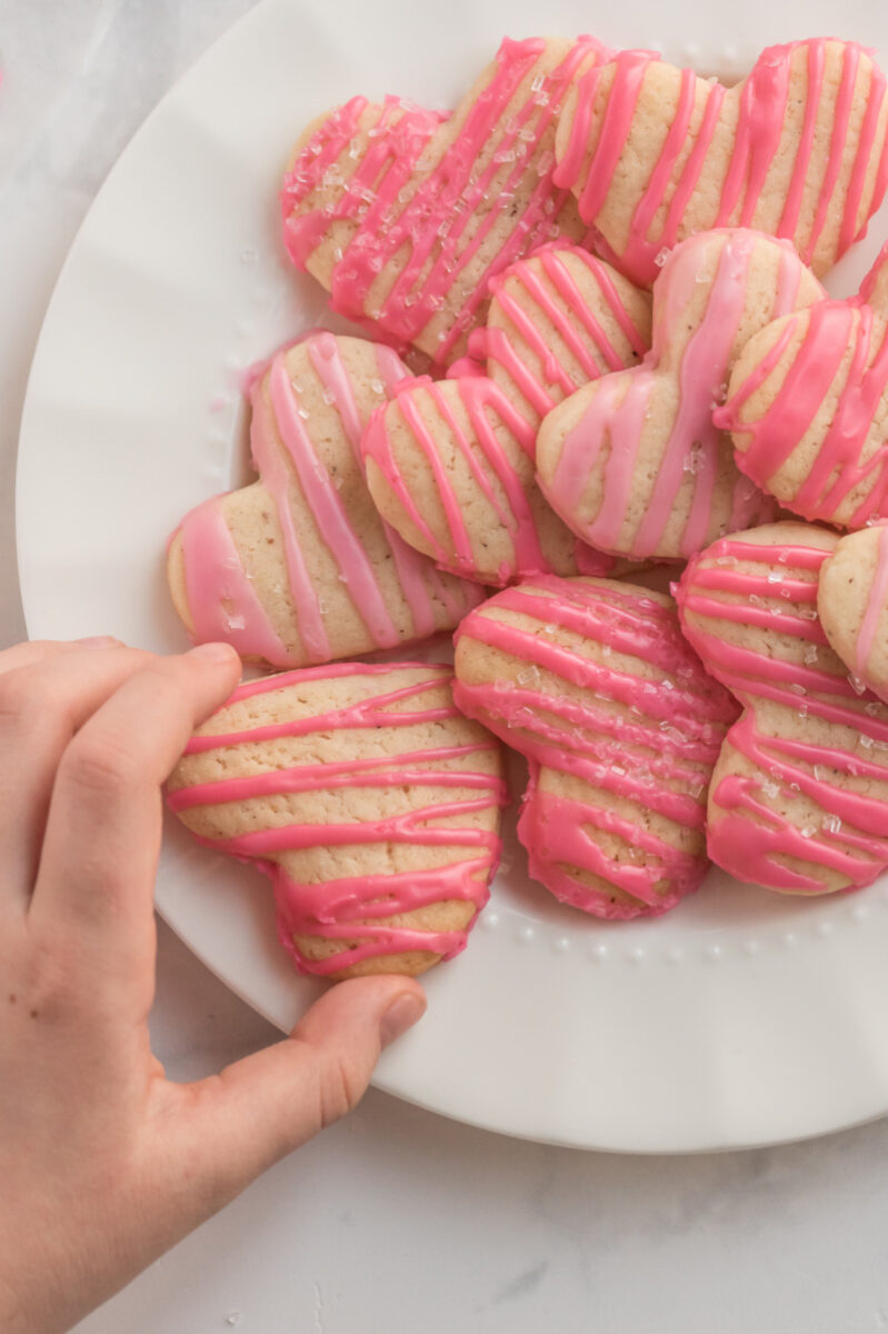 hand taking heart cookie from platter of cookies