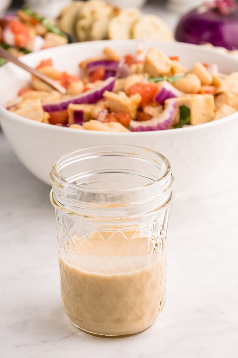 jar of salad dressing in front of salad