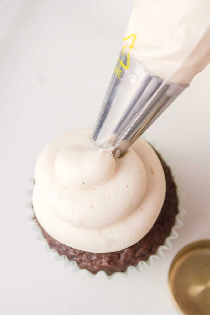 piping white icing onto cupcake