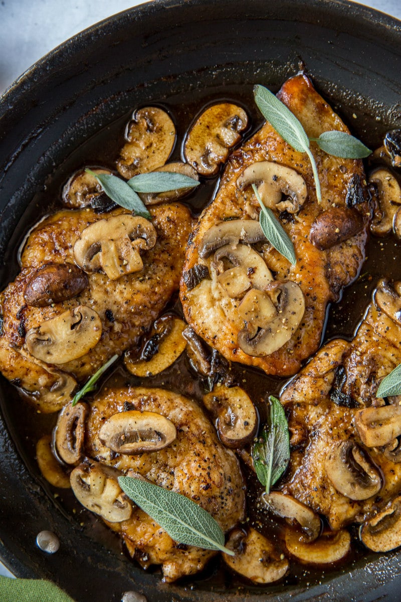 chicken marsala garnished with fresh sage in a skillet