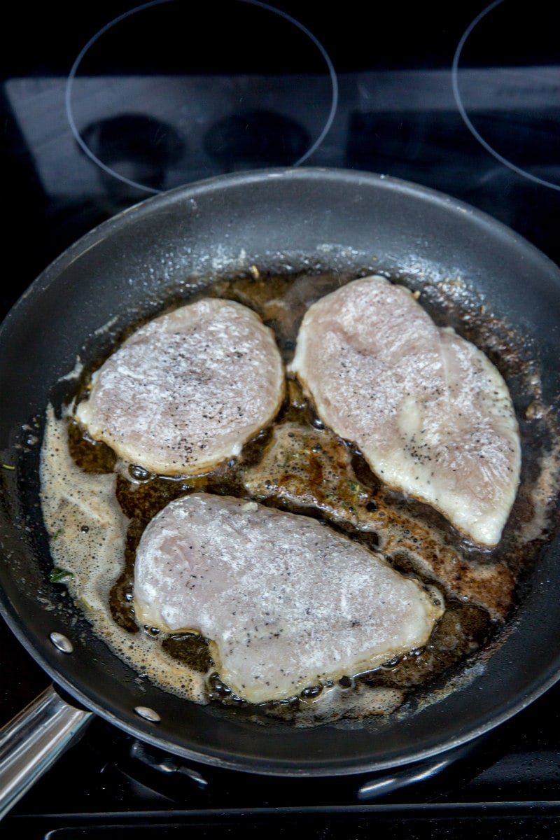 chicken breasts cooking in oil in a hot skillet