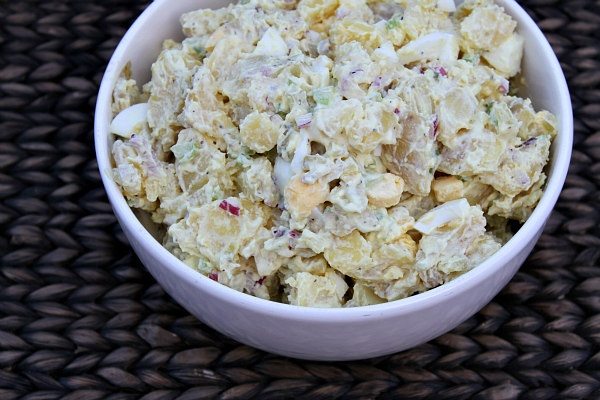 white bowl of All American Potato Salad set on a woven placemat