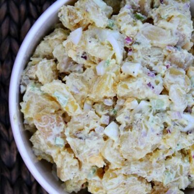 overhead shot of all american potato salad in a white bowl set on a woven placemat