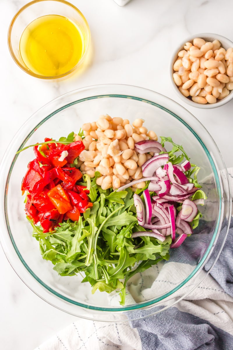 arugula, roasted red pepper, red onion and white beans in a bowl