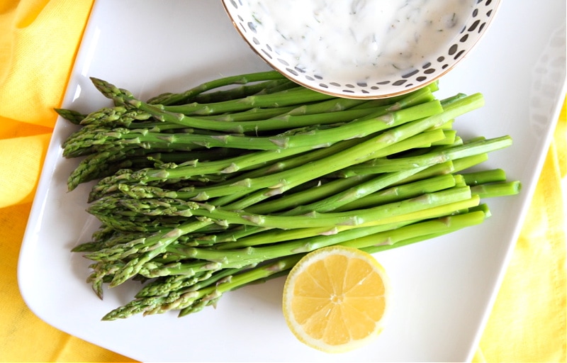 asparagus and lemon on a platter with sauce on side