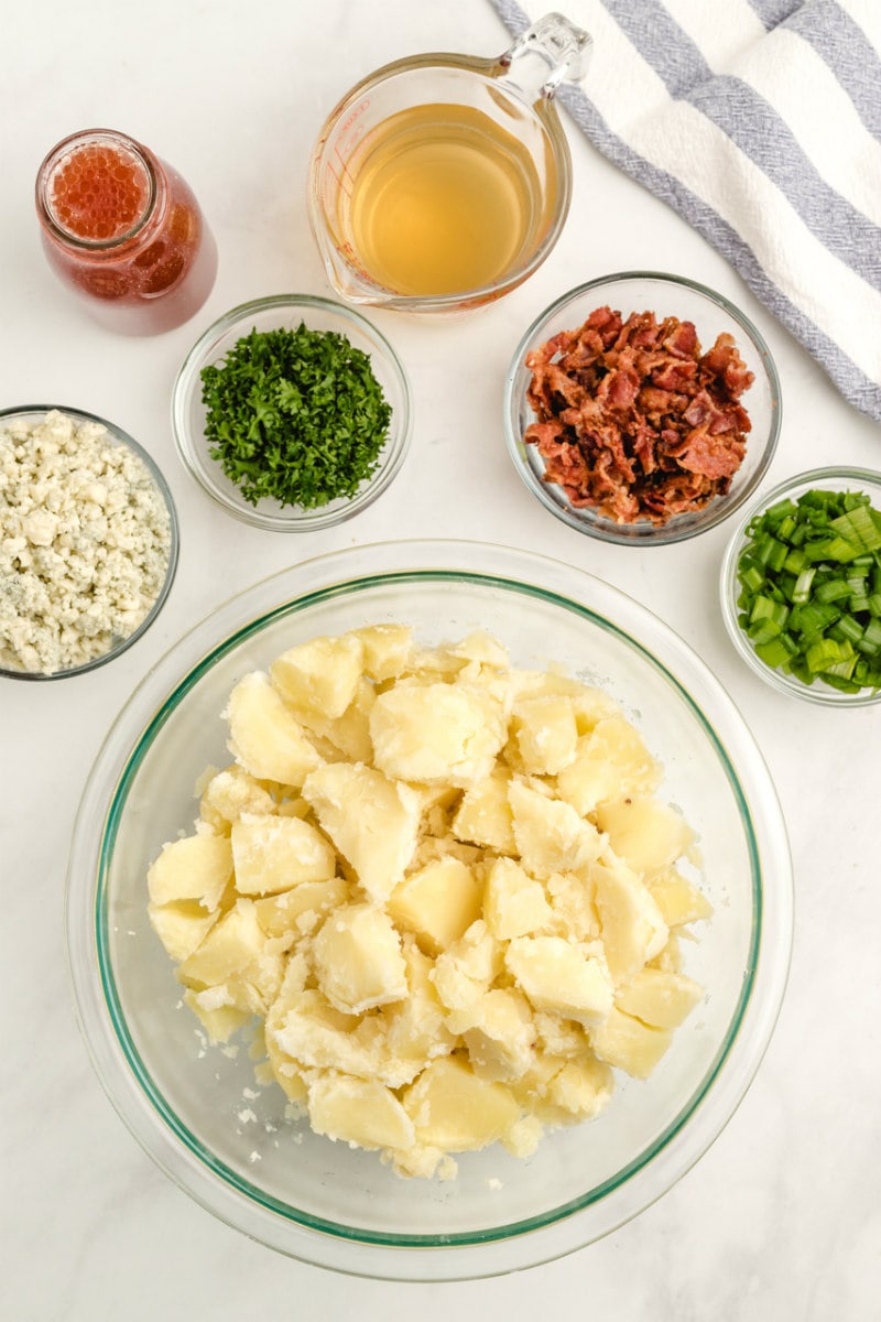 overhead display of ingredients needed for blue cheese and bacon potato salad in glass bowls