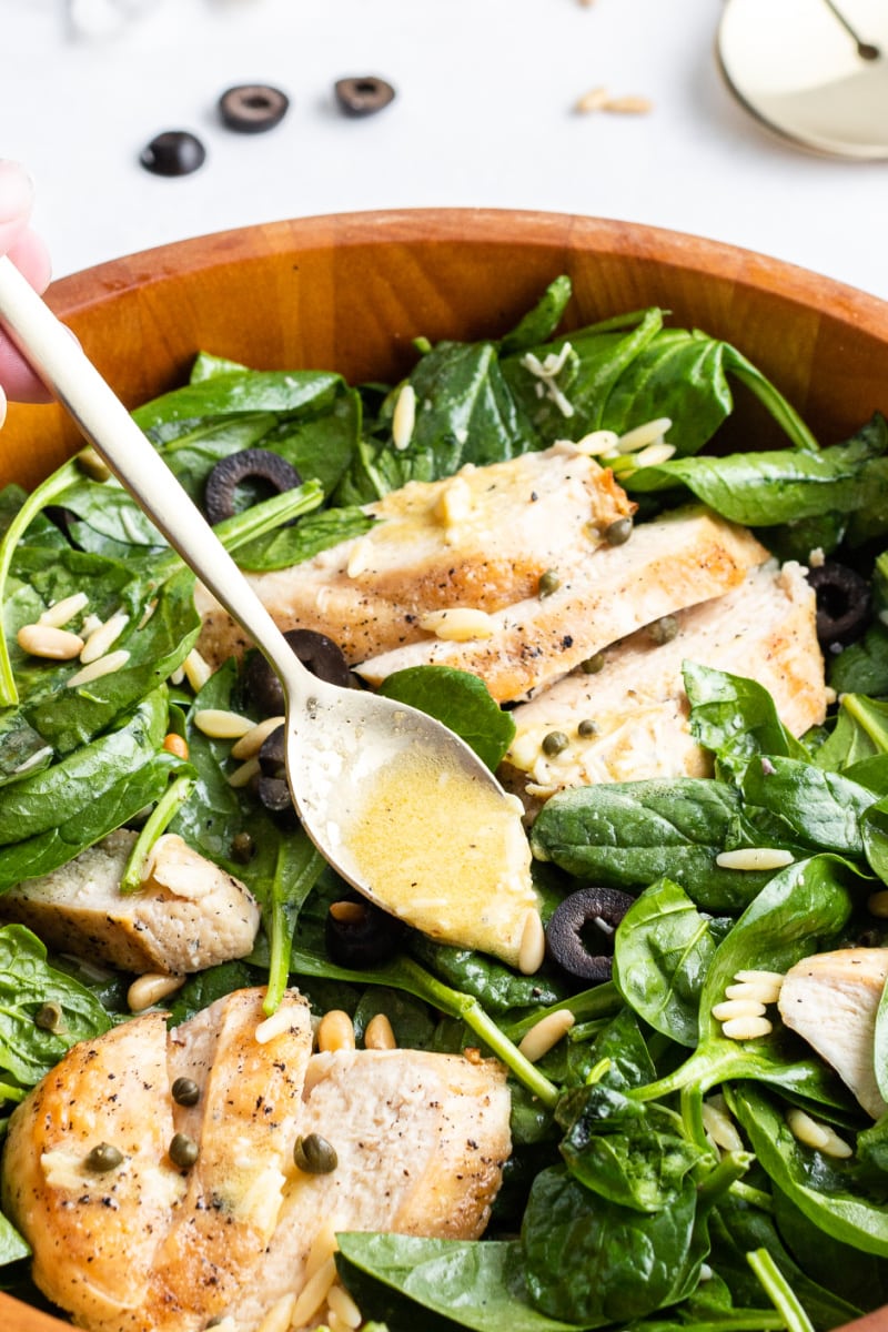 spooning dressing onto bowl of chicken florentine salad