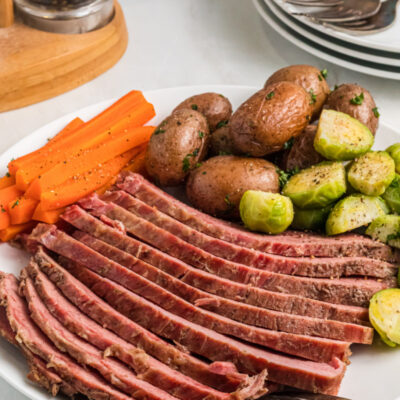 sliced corned beef on a plate with veggies