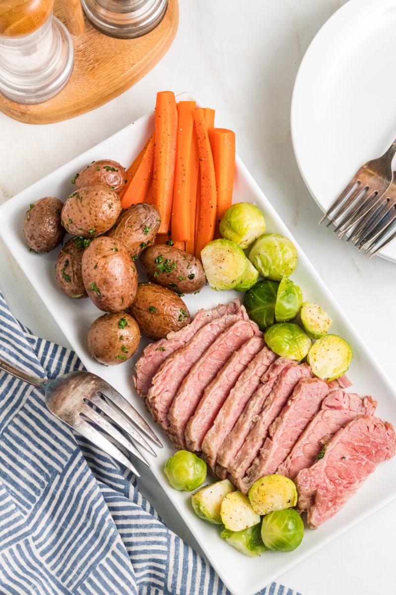 classic corned beef on a platter with potatoes, carrots and brussels sprouts