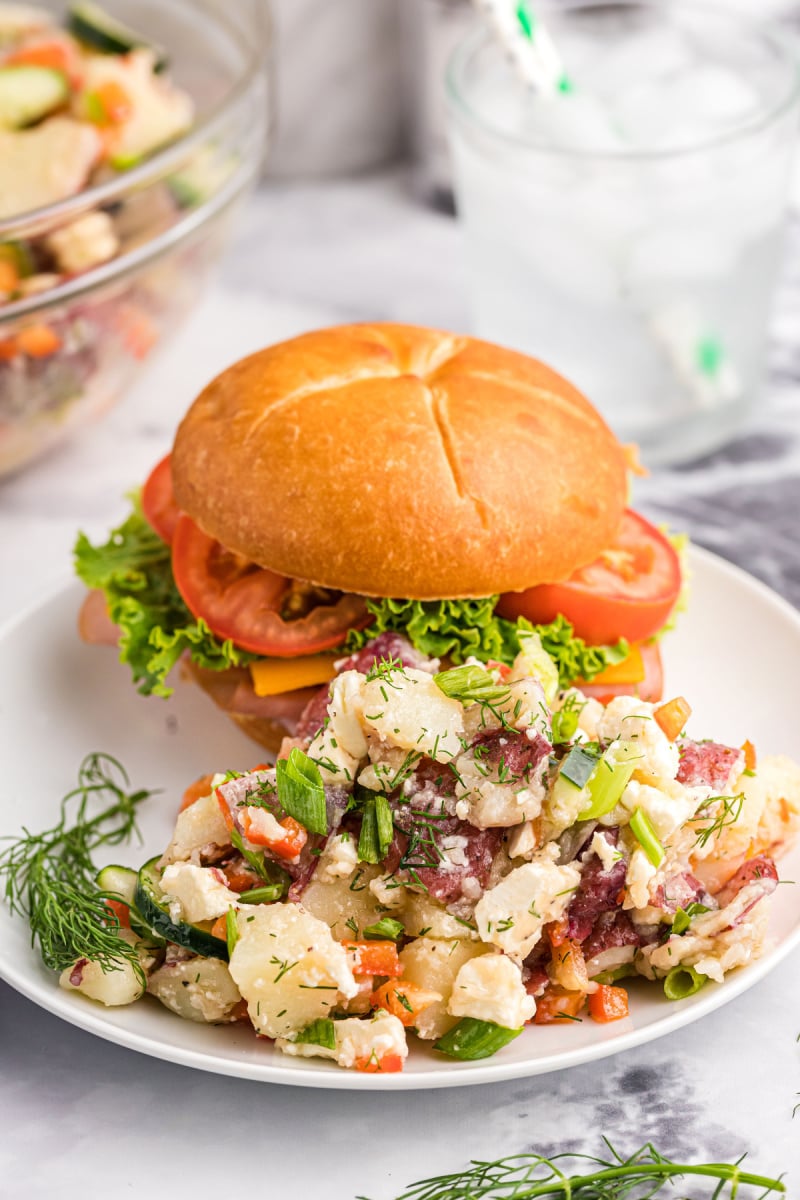 dill potato salad on a plate with a burger