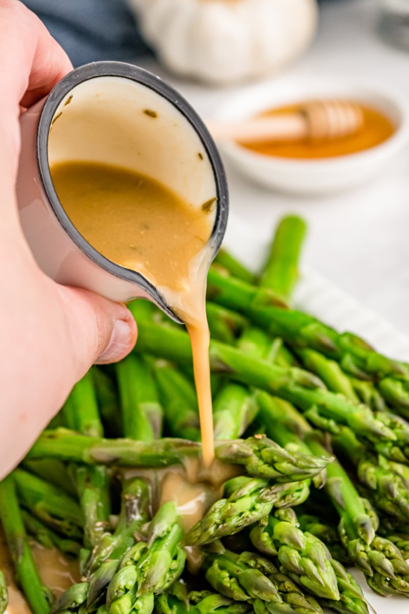 pouring dressing onto asparagus