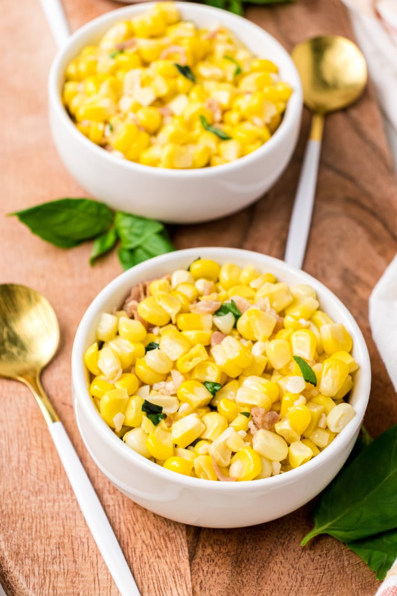 two servings in small bowls of fresh corn with prosciutto basil butter