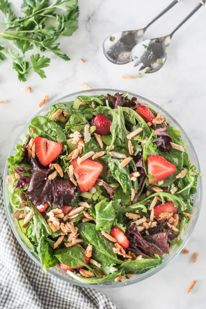 bowl of green salad with strawberries and sugared almonds