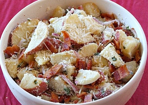 Lemon Basil Roasted Potato Salad in a white bowl with a red background