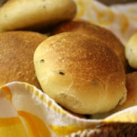 olive oil and rosemary rolls in a basket with a napkin