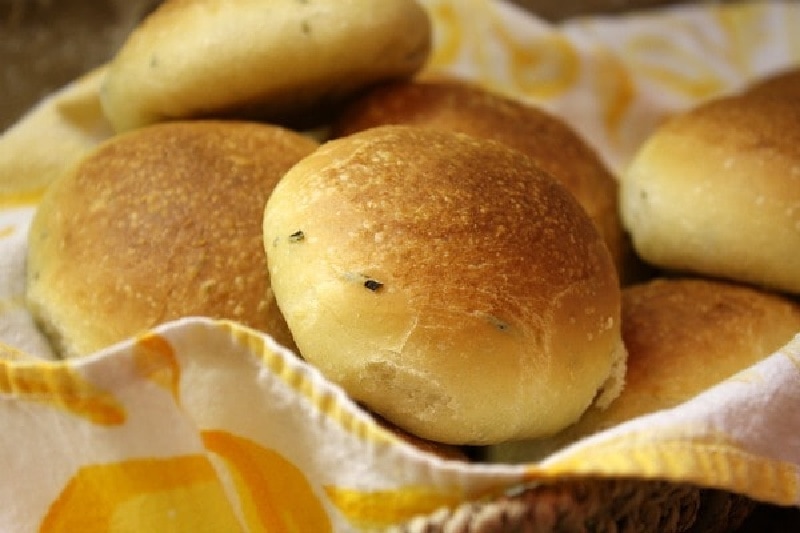 olive oil and rosemary rolls in a basket with a napkin