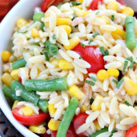 white bowl of orzo salad with corn green beans and tomatoes