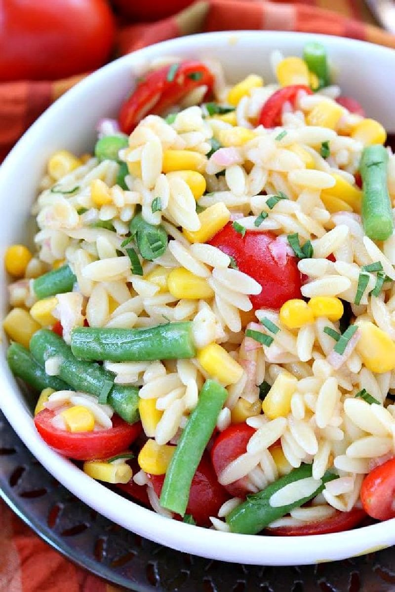 white bowl of orzo salad with corn green beans and tomatoes