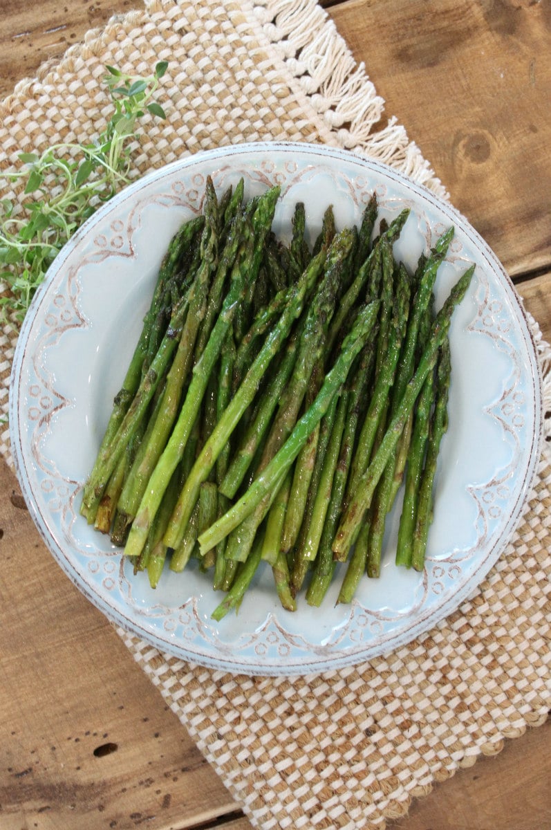 Pan Roasted Asparagus with Thyme recipe from RecipeGirl.com #pan #roasted #panroasted #asparagus #thyme #recipe #RecipeGirl Pan Roasted Asparagus on a serving plate with fresh thyme