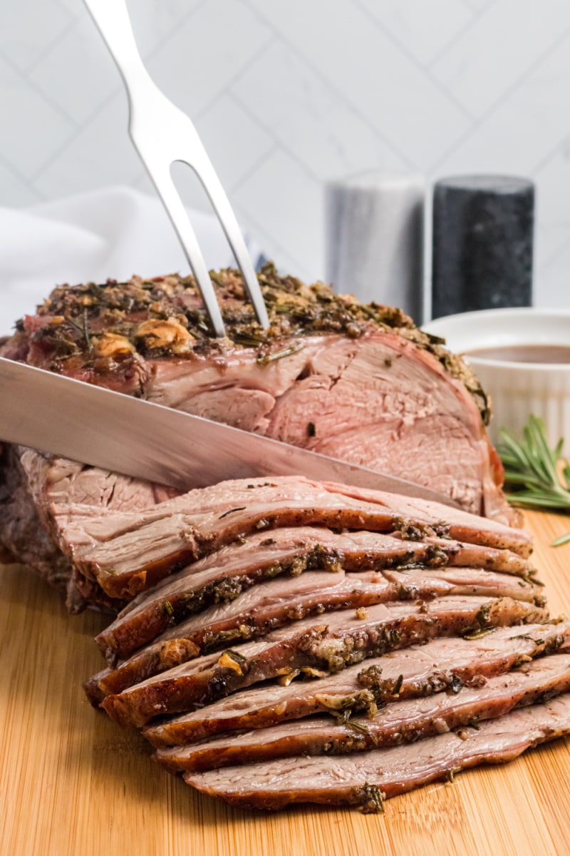 slicing leg of lamb with garlic and rosemary