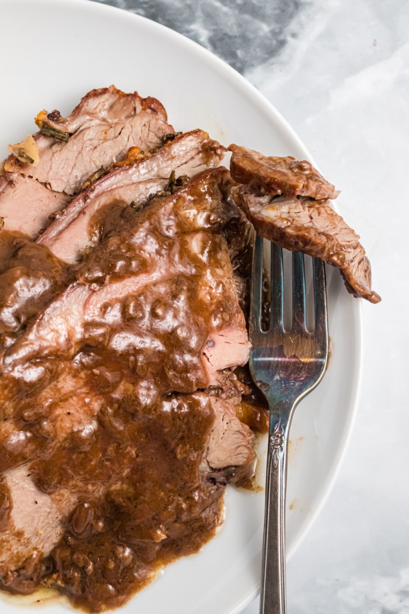 sliced roasted lamb with gravy on a plate