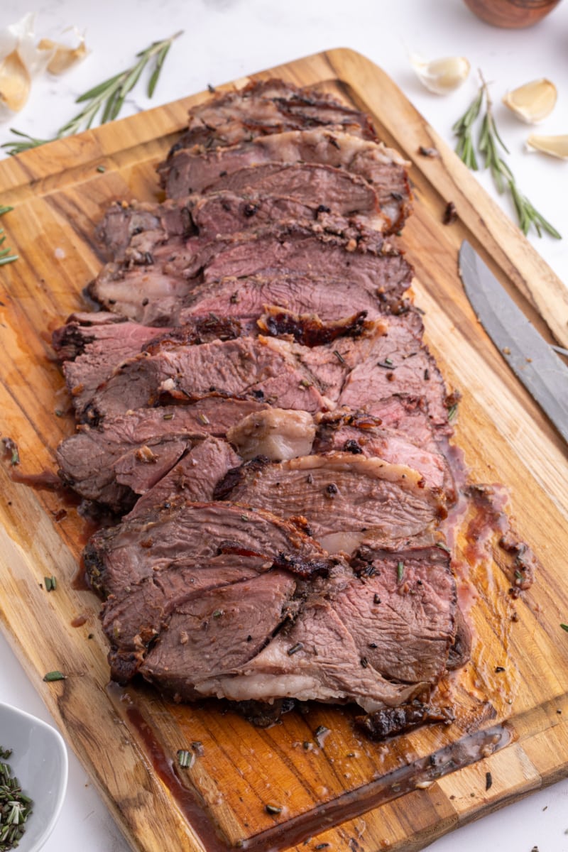 rosemary and garlic leg of lamb roast sliced on cutting board